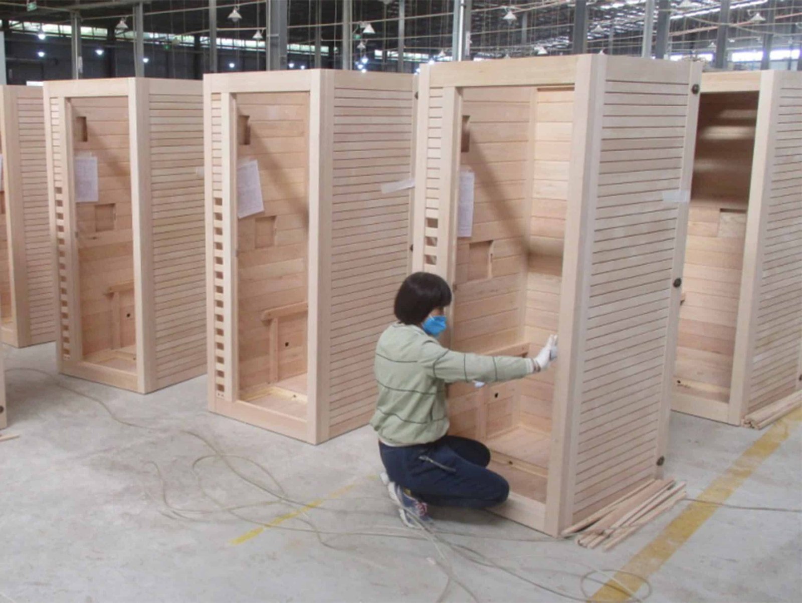 Worker fitting wood panels inside a sauna cabin